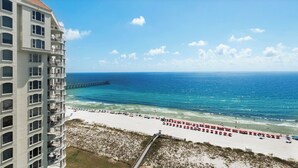 Ein Strandhotel mit Blick auf den Ozean, einen Steg und Strandstühle.
