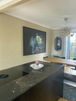 Eine moderne Küche mit dunkler Marmorarbeitsplatte, einer Glasbowl und einem Gemälde eines Engels an der Wand.