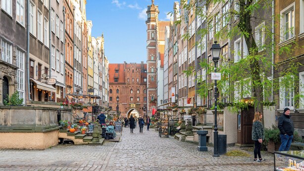 A cobblestone street lined with historic buildings, a prominent church tower, and outdoor market stalls. - Leśna Aura by Grand Apartments (Sopot)