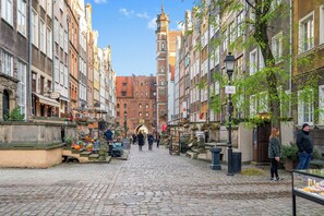 A cobblestone street lined with historic buildings, a prominent church tower, and outdoor market stalls.