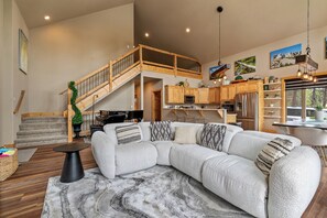 Ein geräumiger Wohnbereich mit Ecksofa, einer Treppe und einer Küche mit Holzschränken.