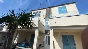A two-story building with a balcony, a door, and a window with blue shutters. - Modern apartment with sea view in the old town of Crikvenica (Crikvenica)