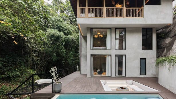 Uma casa moderna com dois andares, piscina, janelas amplas e uma varanda.