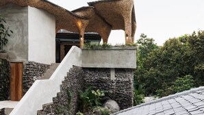 Uma casa moderna com escadaria de pedra, porta de madeira e design de telhado único.