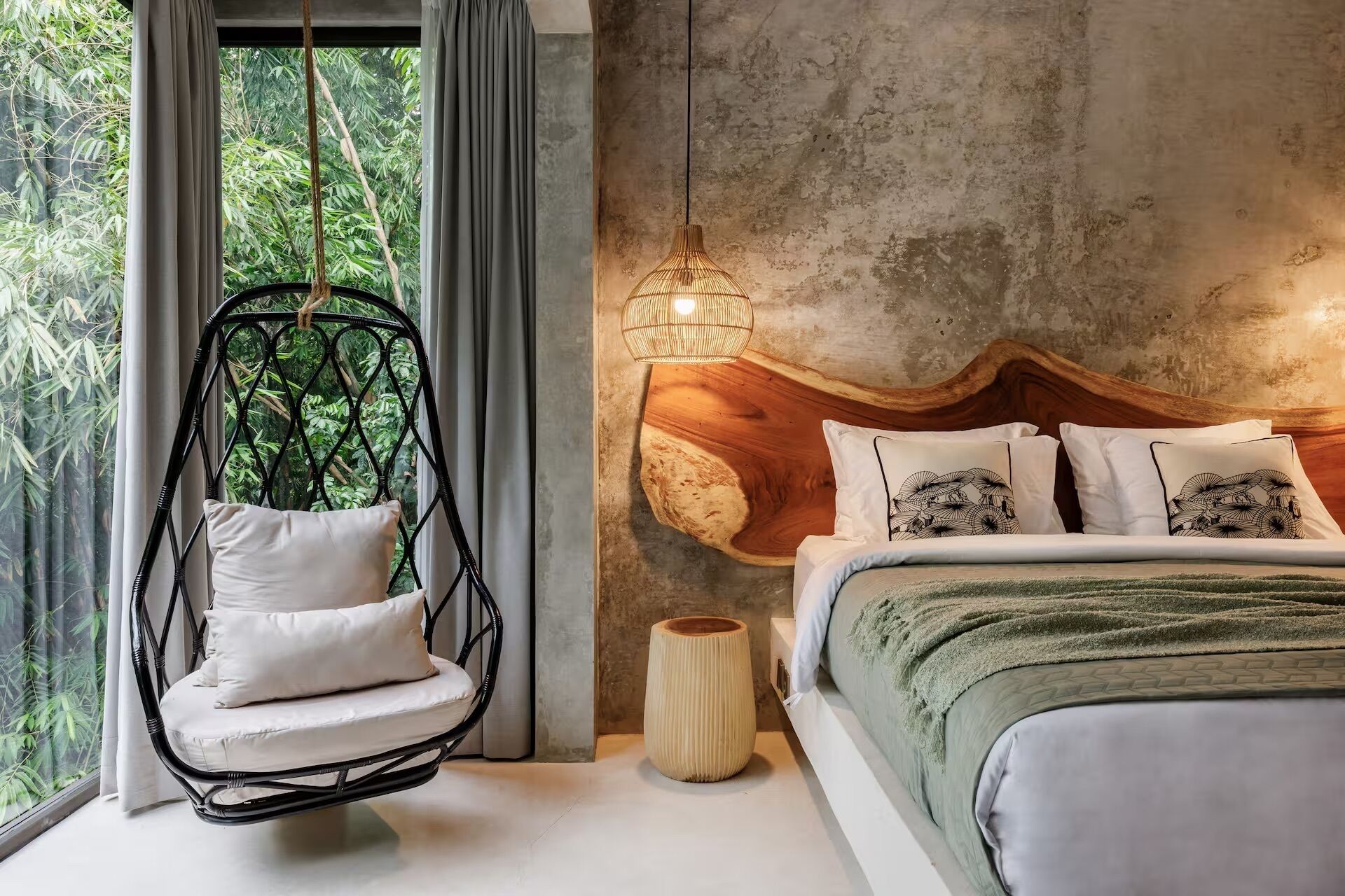 A bedroom with a hanging chair, a bed with patterned pillows, and a unique wooden headboard.