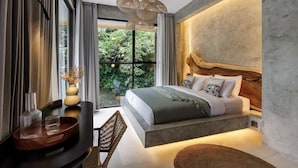 Quarto moderno com uma cama grande, cabeceira de madeira, área de refeições com mesa e cadeiras, e vista para o verde lá fora.