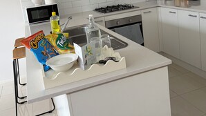 Eine moderne Küche mit weißen Schränken, einer eingebauten Mikrowelle, einem Gasherd und einem Spülbecken.
