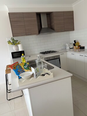 Una cocina moderna con encimera blanca, microondas, estufa y armarios.