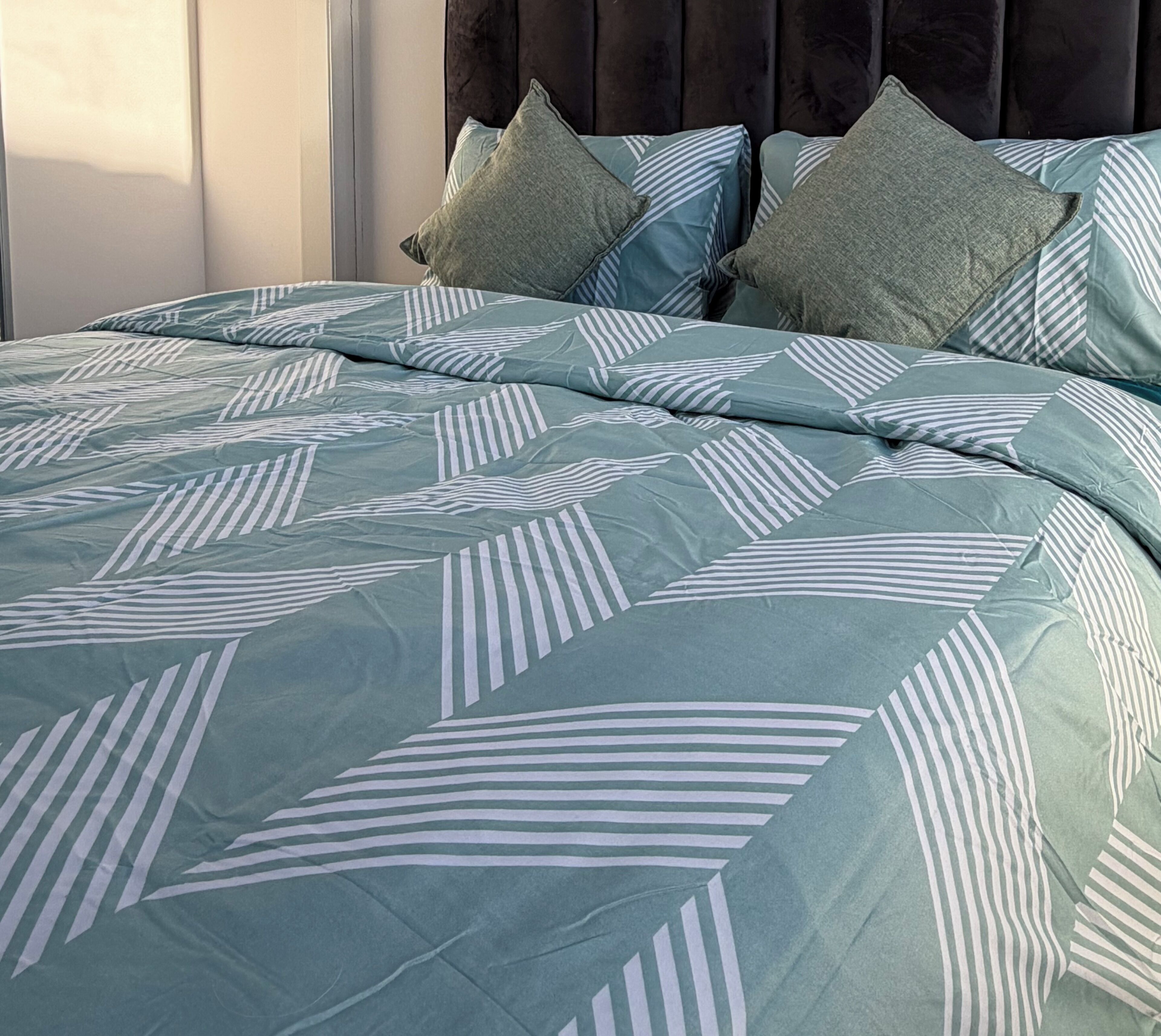 A bed with a patterned bedspread and pillows.