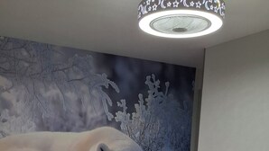 Ein Schlafzimmer mit einem Bett, einer Wandmalerei von Eisbären und einer Deckenleuchte.