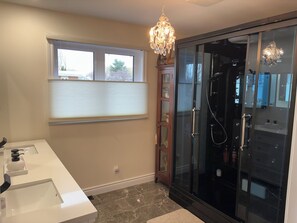 Une salle de bain moderne avec une douche à parois de verre, un meuble-lavabo à deux vasques et un lustre.