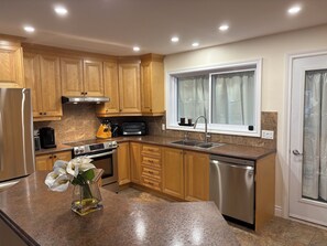 A modern kitchen with wooden cabinets, stainless steel appliances, a built-in oven, and a dishwasher.