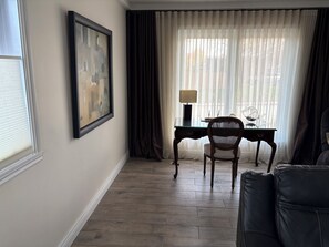 A hotel room with a desk, chair, and a large framed picture on the wall.
