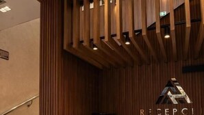 A reception desk with a wooden panel design and a logo above it. - Hotel Astral (Šabac)