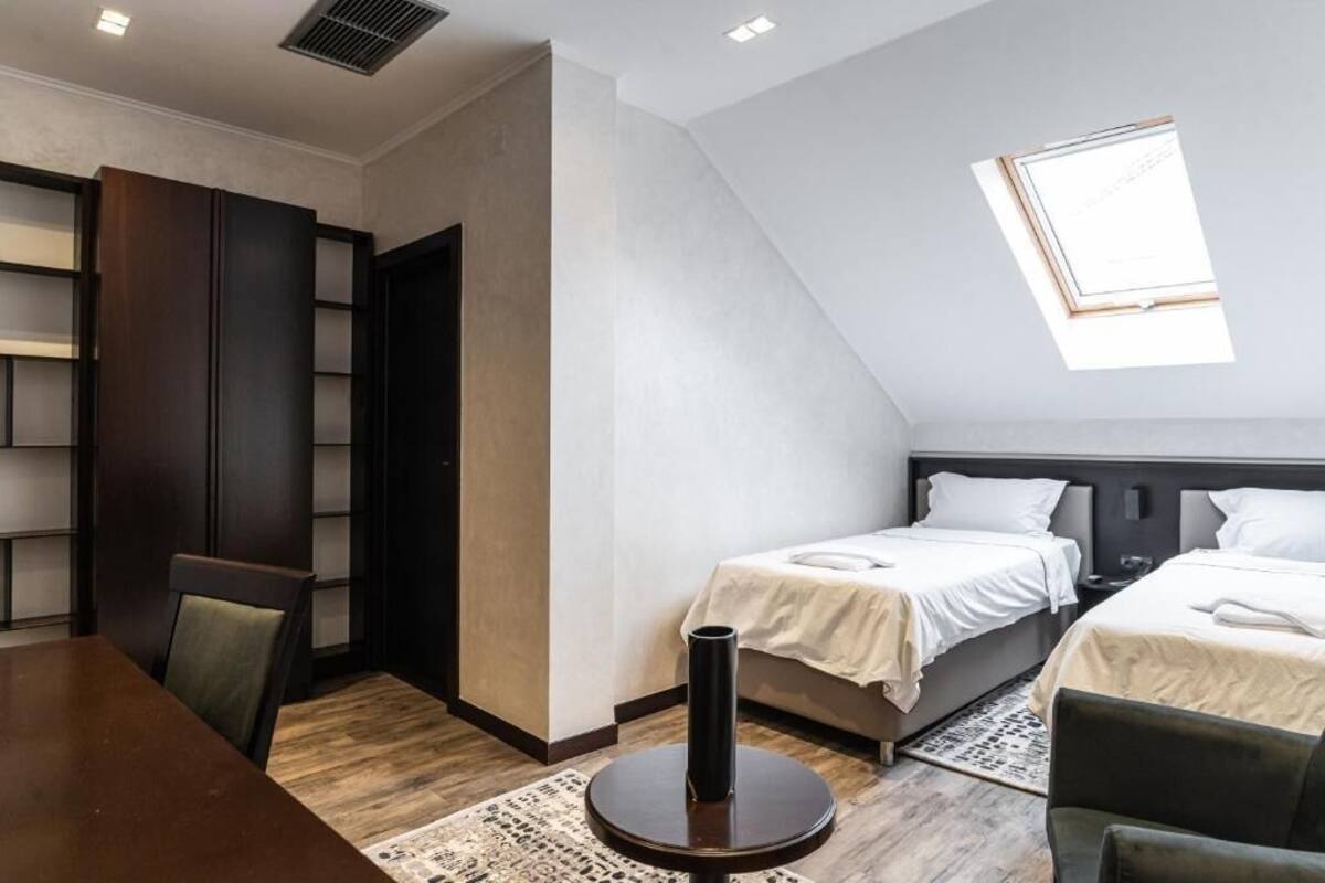 Una habitación con dos camas, una mesa de comedor y una estantería.