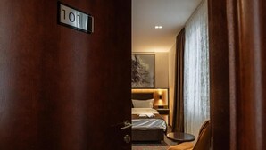 A hotel room with a bed, a bedside table, a chair, and a painting on the wall. - Hotel Astral (Šabac)