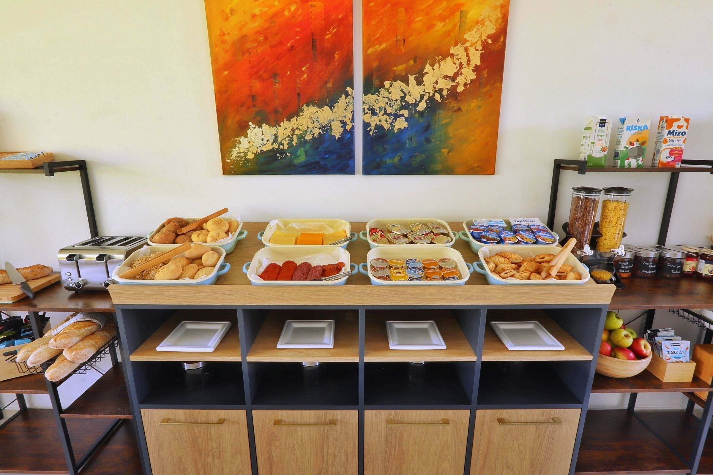 A buffet setup with various food items and condiments, a toaster, and a coffee machine.