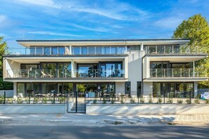 Ein modernes, mehrstöckiges Gebäude mit Balkonen, Außenbereich und blauem Himmel.