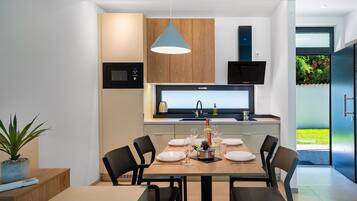 A modern kitchen with a dining area, a microwave, a sink, and a pendant light.