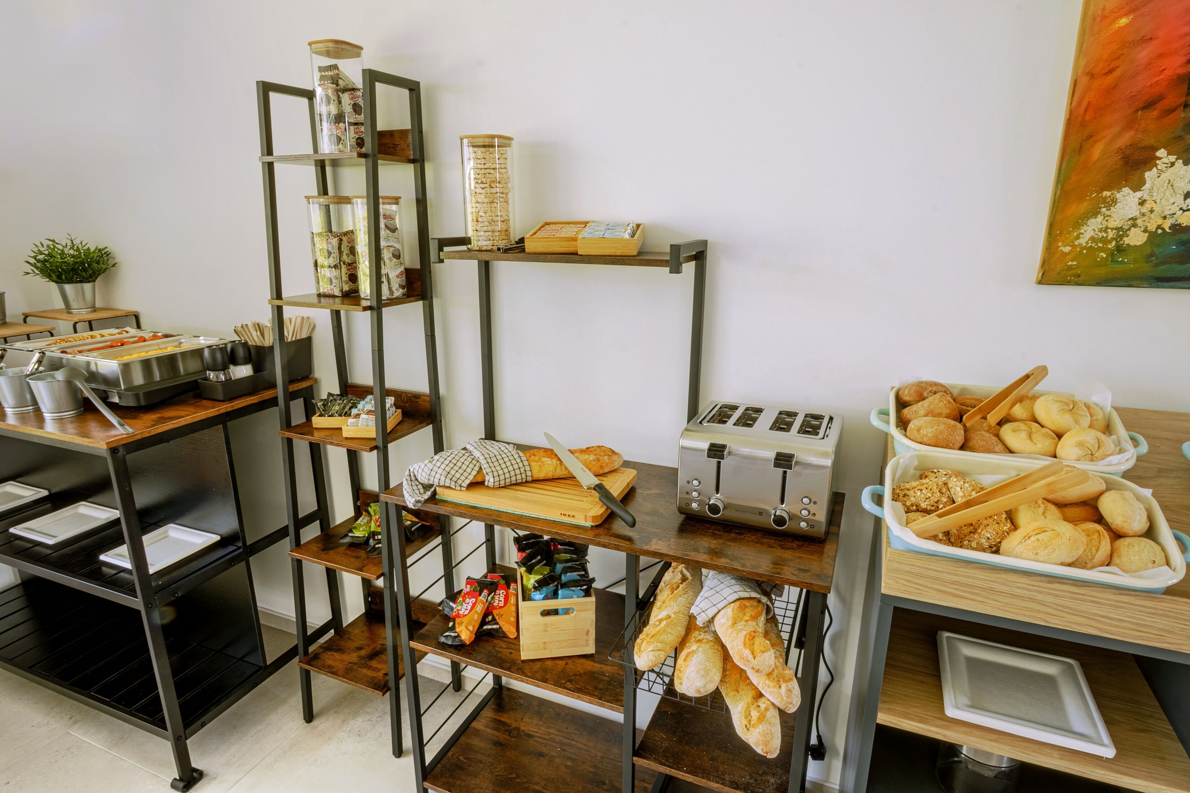 A kitchen with shelves holding various food items, a toaster, and a plant.
