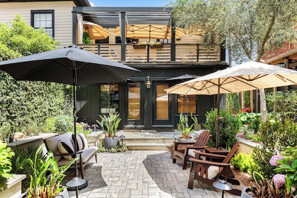 Eine Terrasse mit Sitzgelegenheiten, Sonnenschirmen und Topfpflanzen.