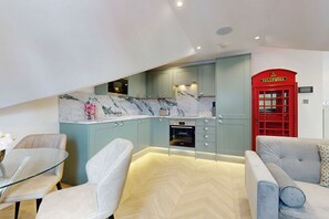 A modern kitchen with marble countertops, built-in appliances, and a red telephone booth. - Stunning 2BR Home Near Kew-2min walk to Tube (Richmond)