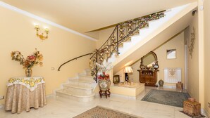 A grand staircase with ornate railings, a chandelier, and a floral arrangement at the base. - Villa Marchese Bed and Breakfast – Deluxe with Balcony (Trecastagni)