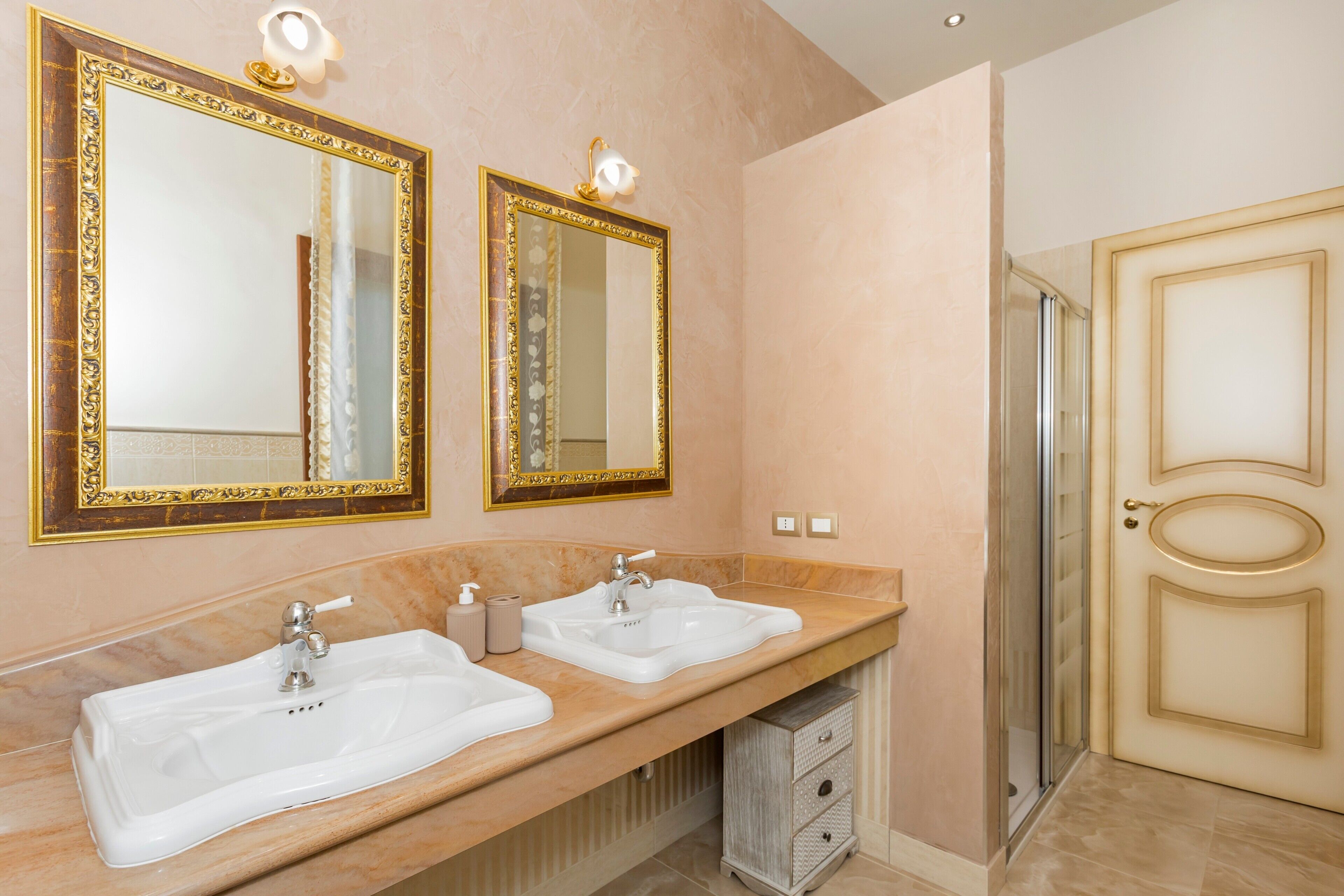 A bathroom with two sinks, a mirror, and a shower.