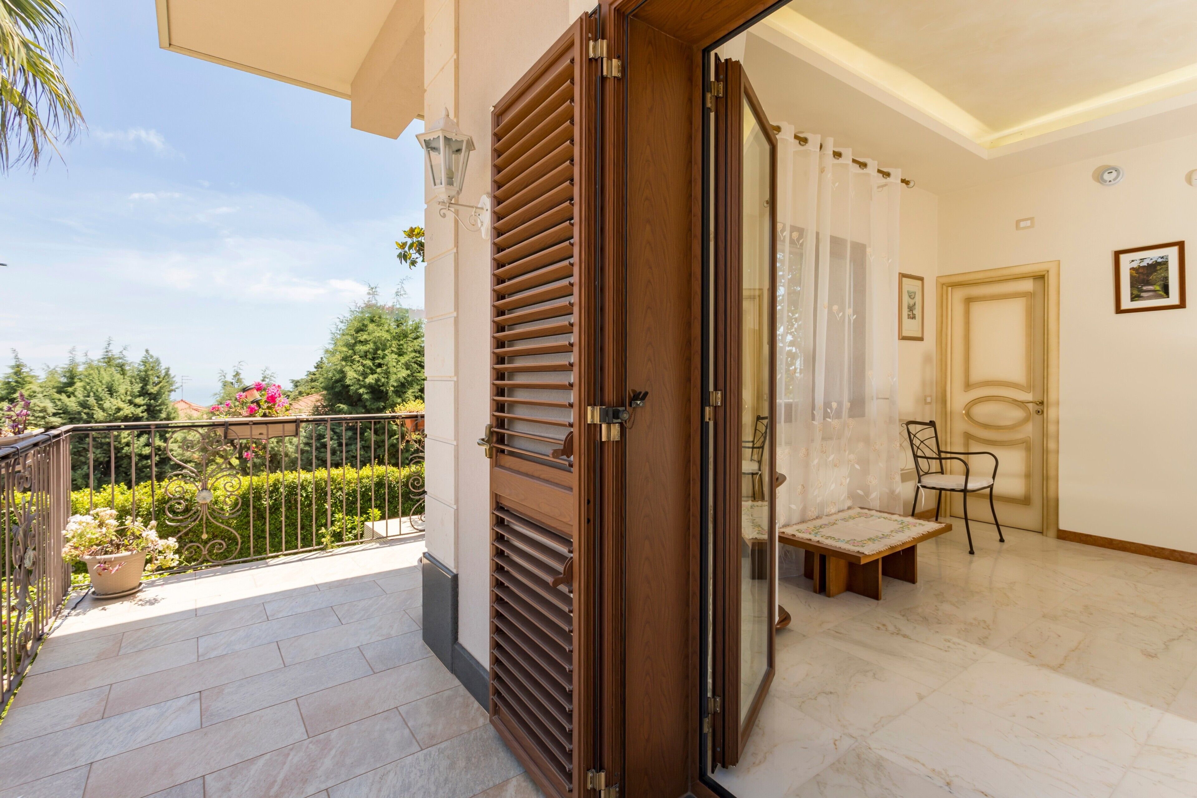 Un balcón con puerta de madera, una silla y una mesa.