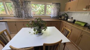 A kitchen with a dining table, chairs, a potted plant, a window with curtains, and kitchen cabinets. - Room-luxury Stay in Pretoria! Fast Wi-fi (Pretoria)