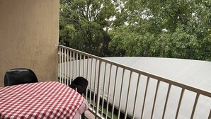 A balcony with a checkered tablecloth, a metal railing, and a view of trees. - Room-luxury Stay in Pretoria! Fast Wi-fi (Pretoria)