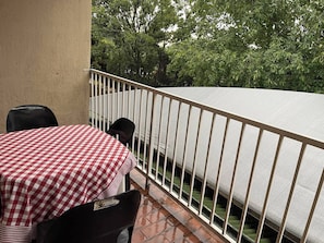 A balcony with a checkered tablecloth, a metal railing, and a view of trees. - Room-luxury Stay in Pretoria! Fast Wi-fi (Pretoria)