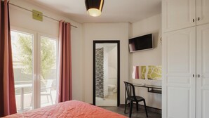Una camera da letto con un letto, una scrivania, una sedia, una televisione e un armadio.
