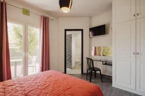 Ein Schlafzimmer mit Bett, Schreibtisch, Stuhl, Fernseher und Kleiderschrank.