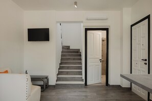 Ein modernes Interieur mit Treppe, Flachbildfernseher, weißer Tür und Sitzbank.