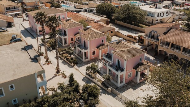 Una zona residenziale con diversi edifici di due piani, alcuni con balconi, e una piscina sullo sfondo.