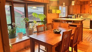 Een houten interieur met een eettafel, stoelen en een keukenhoek.