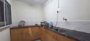 Une cuisine avec des meubles de rangement en bois, un plan de travail noir, un Ă©vier, une fenĂȘtre et une prise Ă©lectrique murale.
