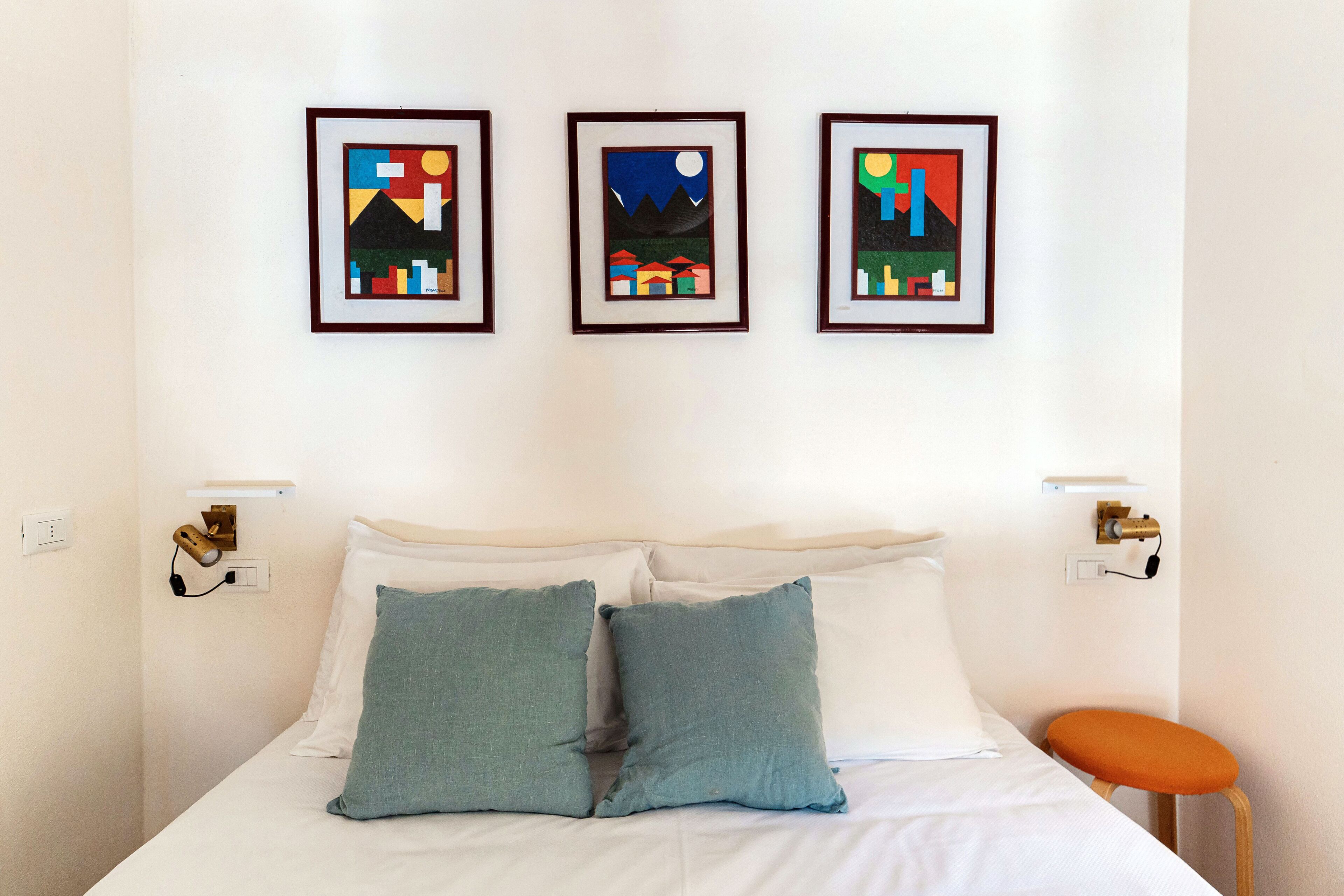 A bed with two pillows, a nightstand, and a framed picture on the wall.