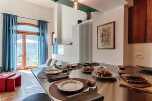 Un comedor con una mesa preparada para el desayuno, un banco rojo y vistas a través de un ventanal.