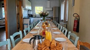Un comedor con una mesa larga dispuesta para el desayuno, que incluye cruasanes y jugo de naranja.