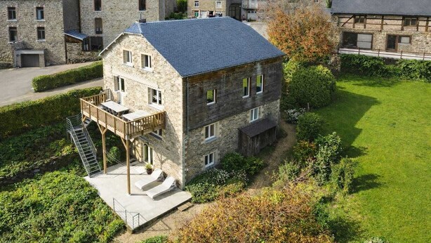 Un edificio de piedra con balcón y un pequeño jardín.
