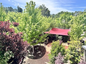 A garden with a red canopy, trees, and a paved walkway.