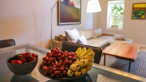 A dining table with a bowl of strawberries and a bowl of grapes and bananas. - Suites On Main (Kelseyville)