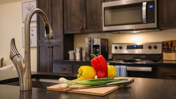 A kitchen with a stainless steel faucet, a microwave, and an oven. - Suites On Main (Kelseyville)