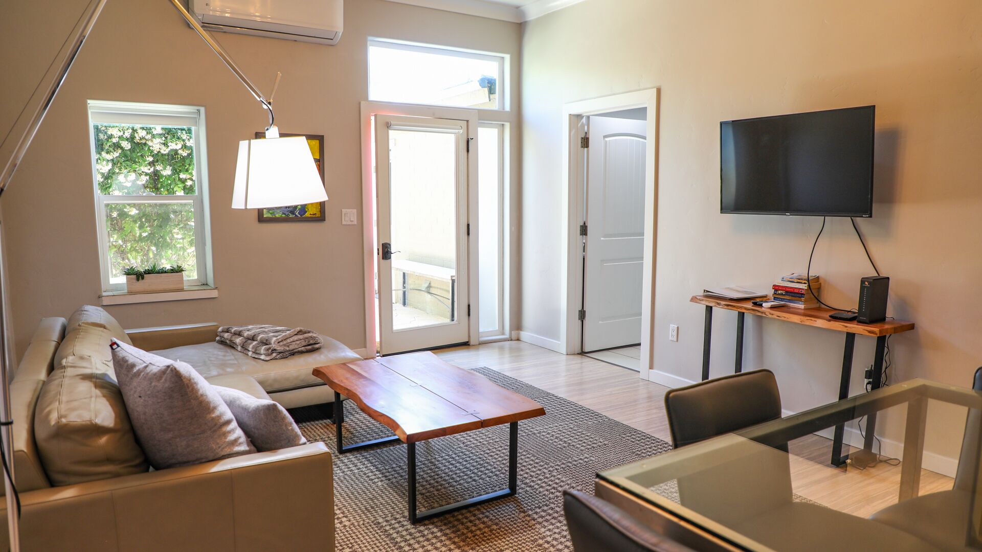 A modern living room with a sofa, coffee table, TV, and a dining area.