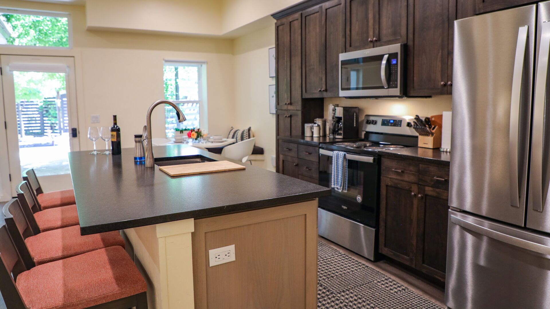 A modern kitchen with a central island, stainless steel appliances, and dark wood cabinets.