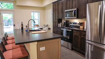 A modern kitchen with a central island, stainless steel appliances, and dark wood cabinets.