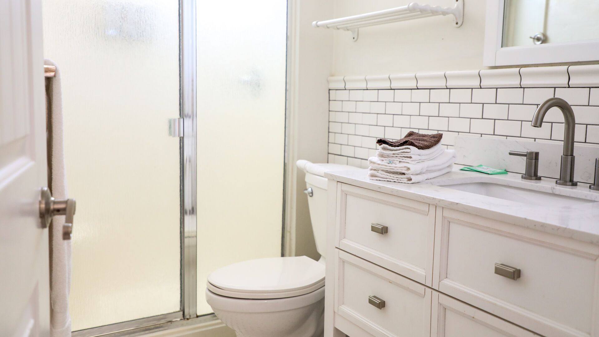 Un baño con inodoro, lavamanos y espejo, y un perchero para toallas.