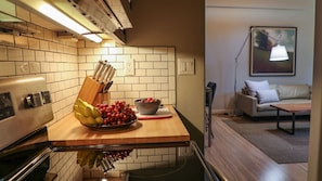 A kitchen with a wooden countertop, a bowl of fruit, and a knife block. - Suites On Main (Kelseyville)